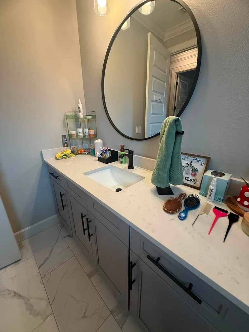 Bathroom vanity with a black-framed oval mirror and green hand towels