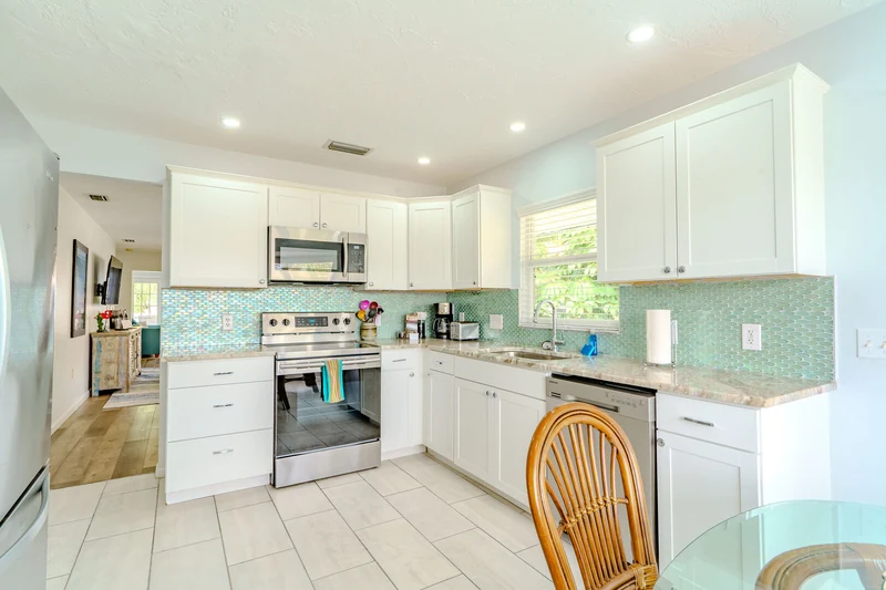 Bright white kitchen with an aqua tile backsplash and stainless steel appliances