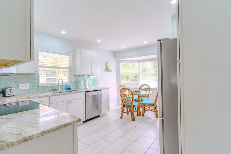 White kitchen with an aqua backsplash and a sunlit breakfast nook