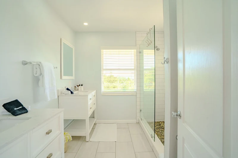 White bathroom with glass shower and folded towels